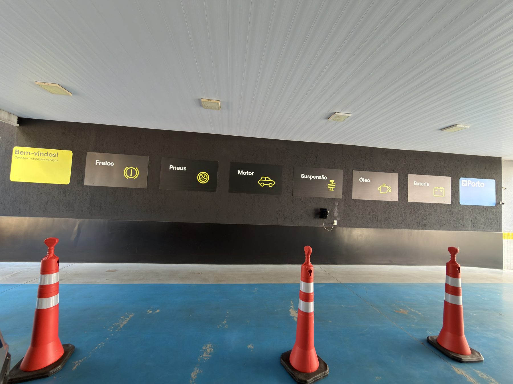 Painel de serviços da rede Porto na parede do Centro Automotivo Âncora: freios, pneus, motor, suspensão, óleo e bateria